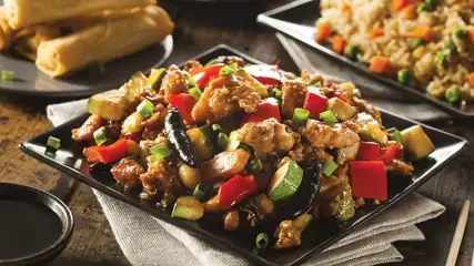 Platter of stir-fry, fried rice, and spring rolls.