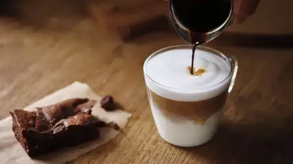 Brownie with a frothy cup of coffee.