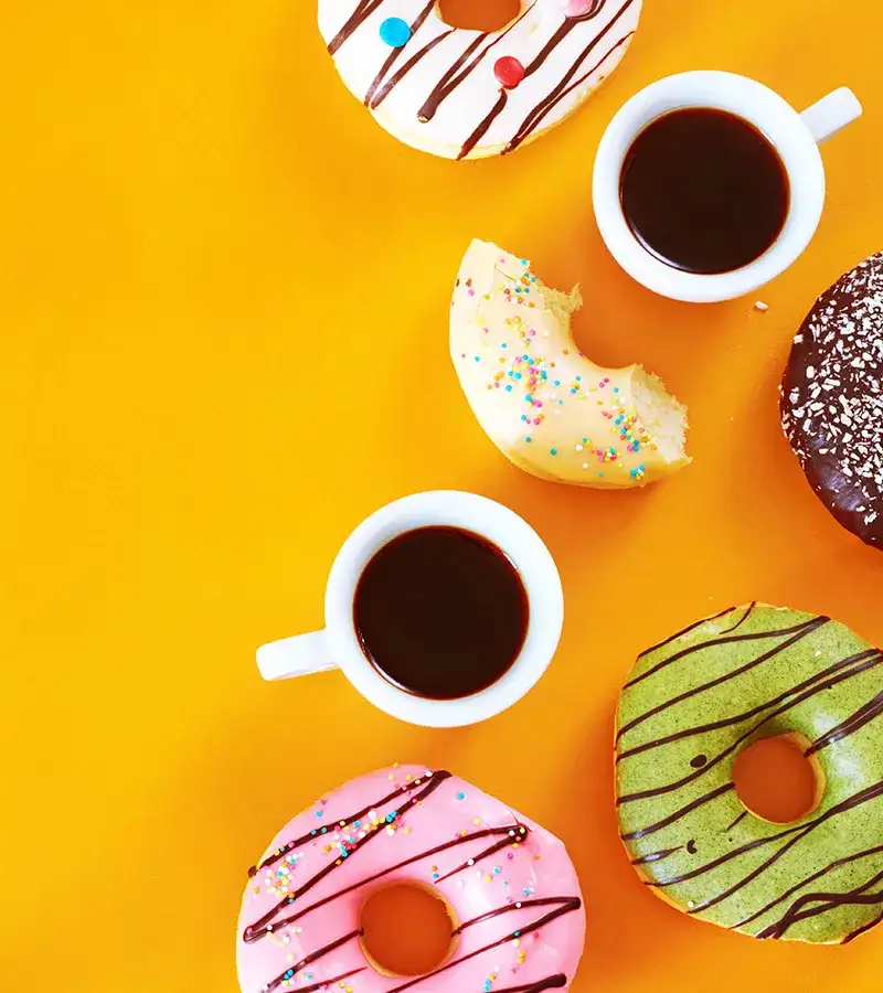 Donuts and mugs of coffee on a yellow background.
