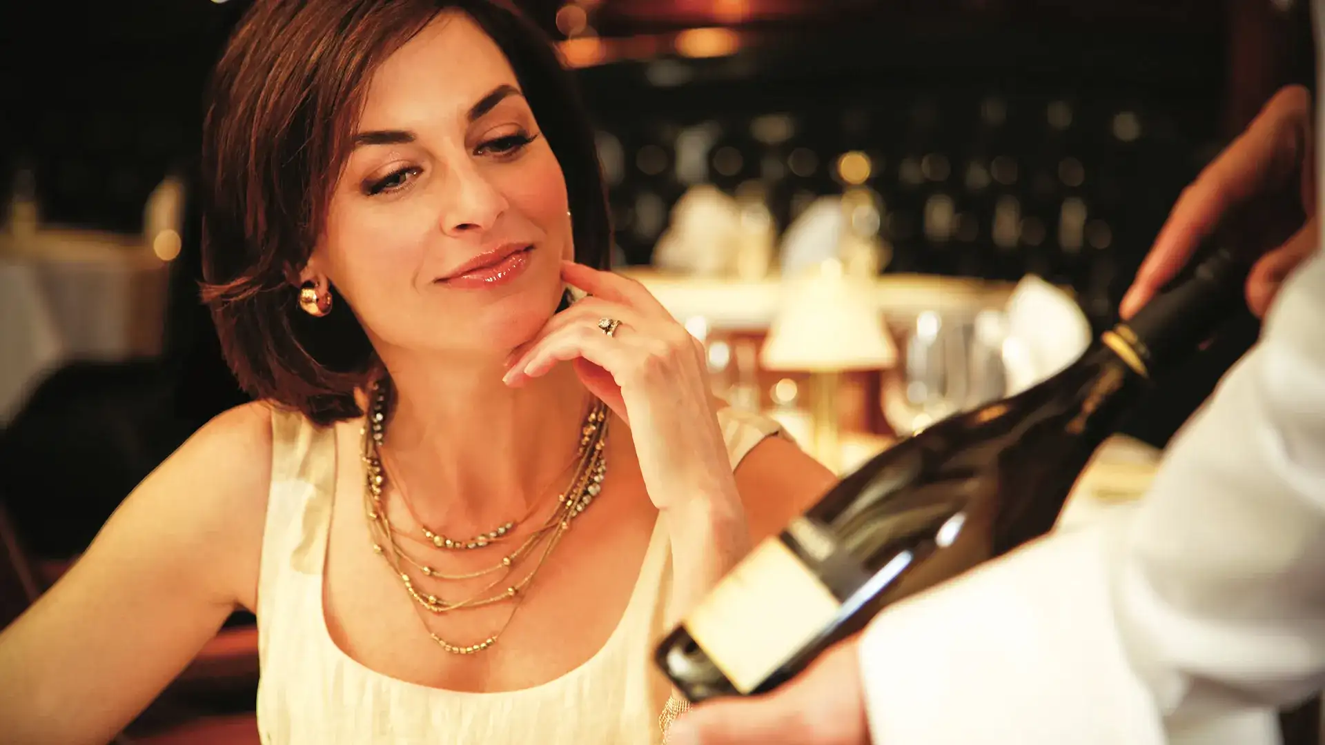 Woman looking at wine bottle.