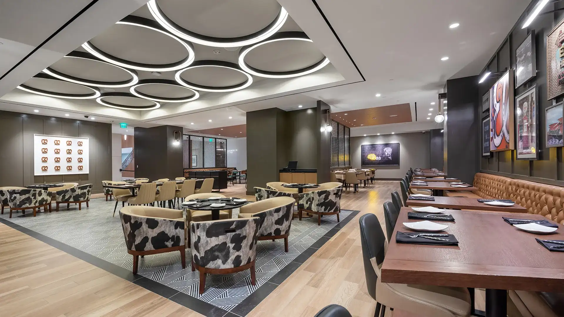 Open dining area with circular ceiling light fixtures, artwork, tables, and chairs.