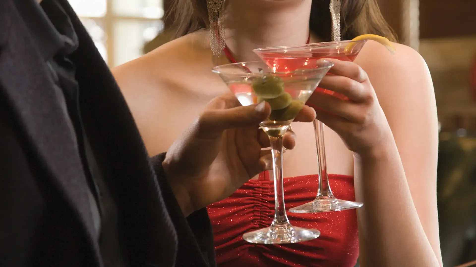 A dressed up couple toasting with a martini and a cosmopolitan cocktail