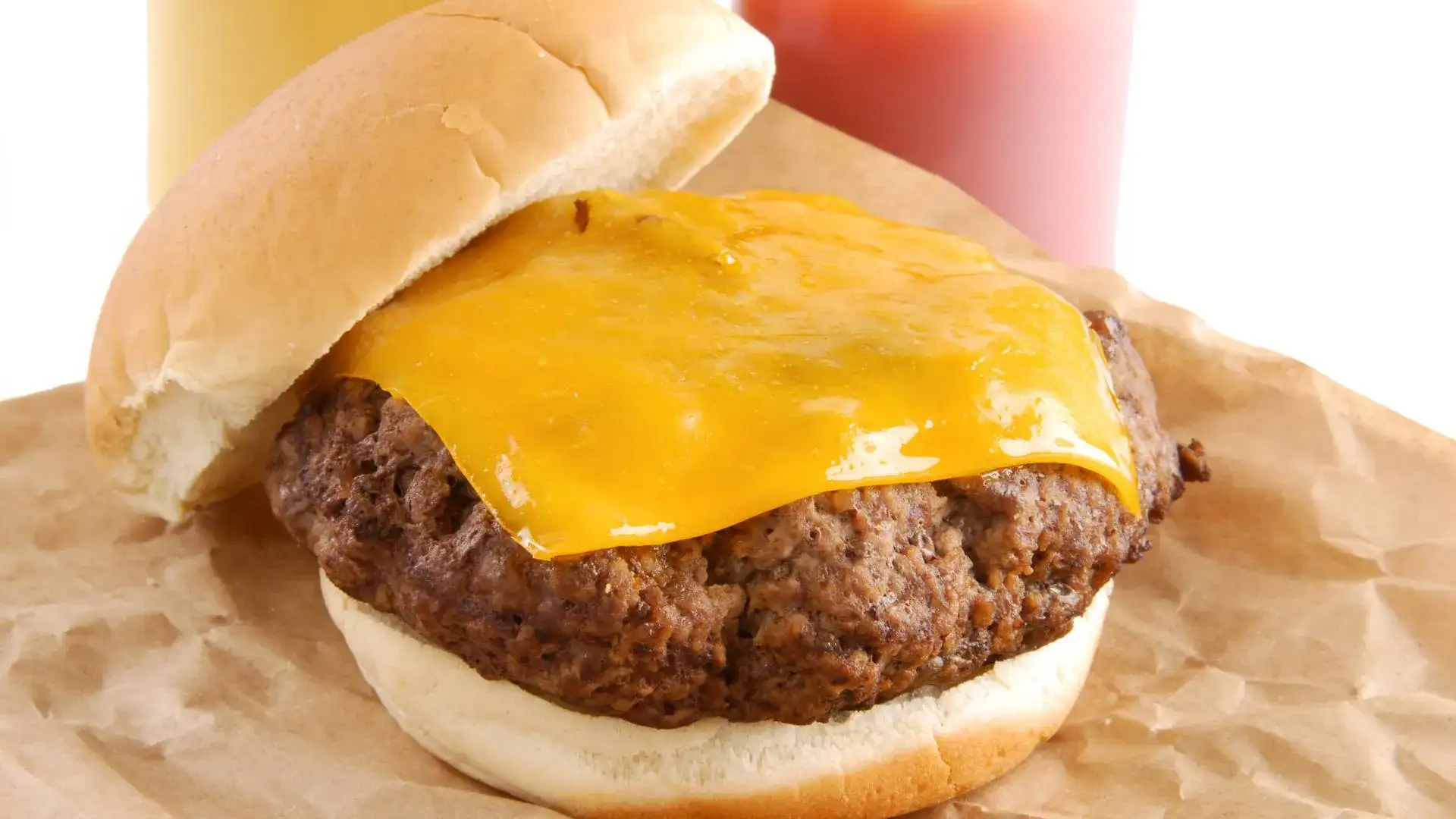 Cheese burger sitting on a paper bag with no condiments added