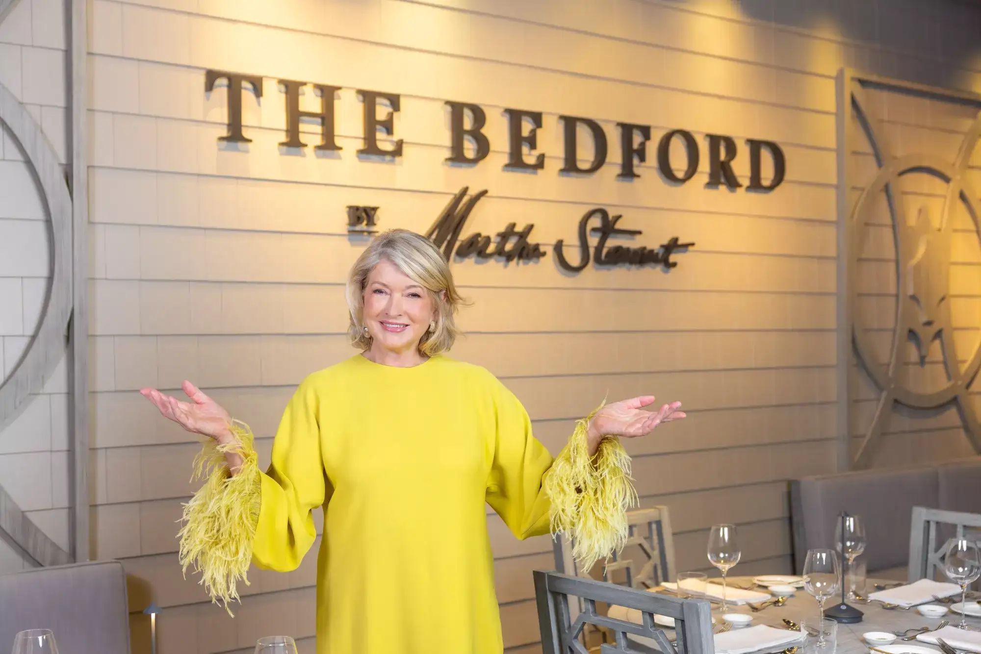 Martha Stewart posing in front of The Bedford sign