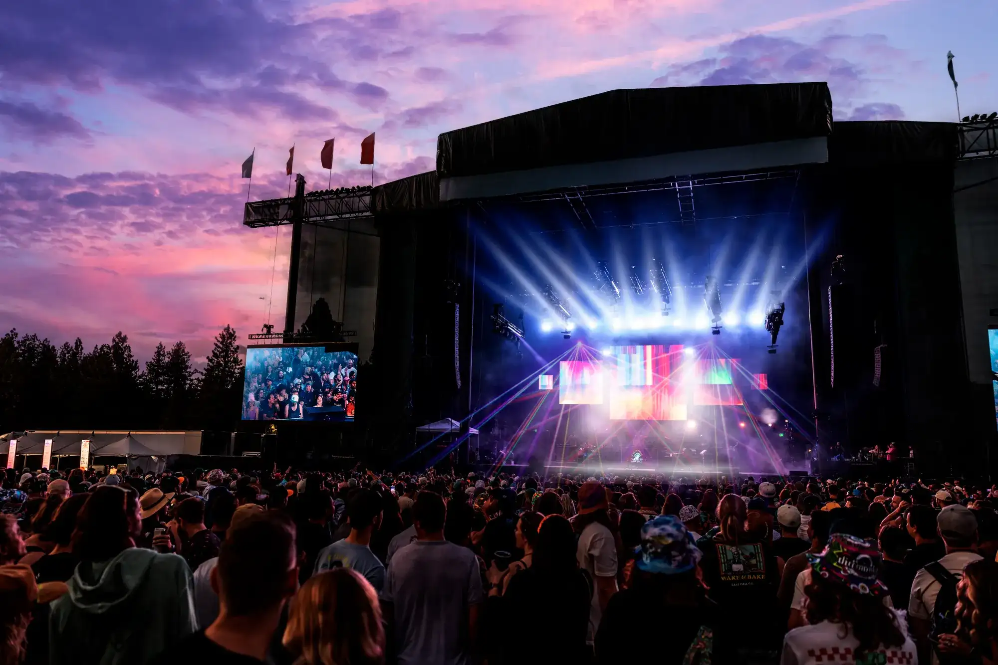 Large crowd gathered at an outdoor concert venue in South Lake Tahoe with a brightly lit stage at sunset.
