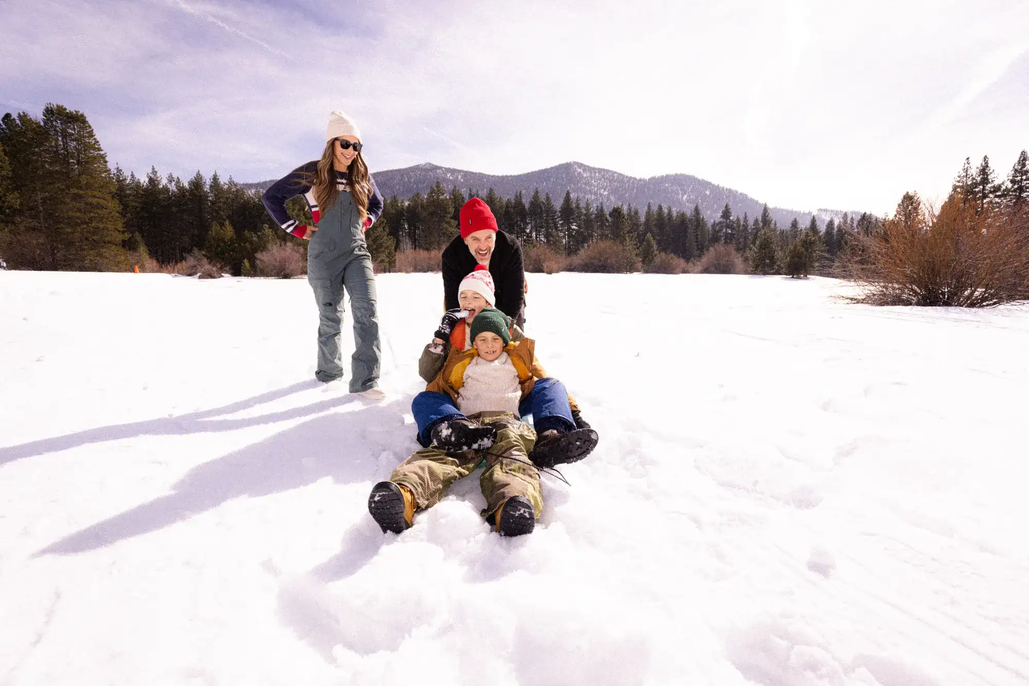Family spending time together outdoors in the snow with mountain scenery and trees in South Lake Tahoe