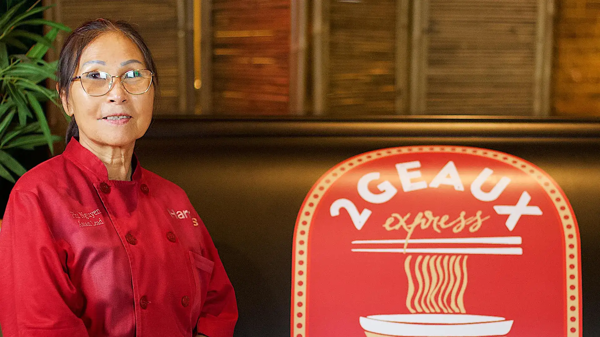 Mrs. Phi beside the 2Geaux Pho Bar sign.