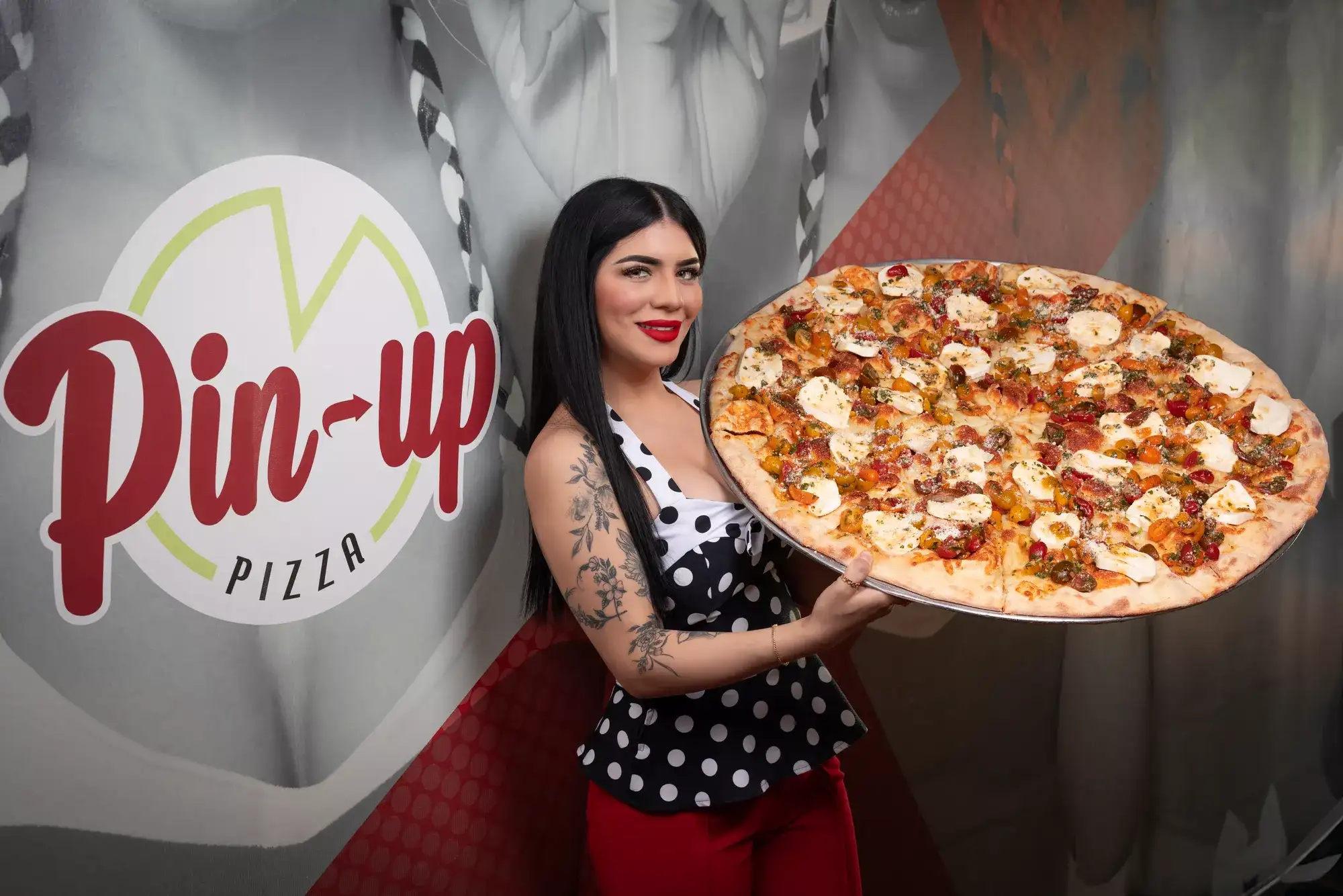 Woman holding up a pizza at Pin-up Pizza