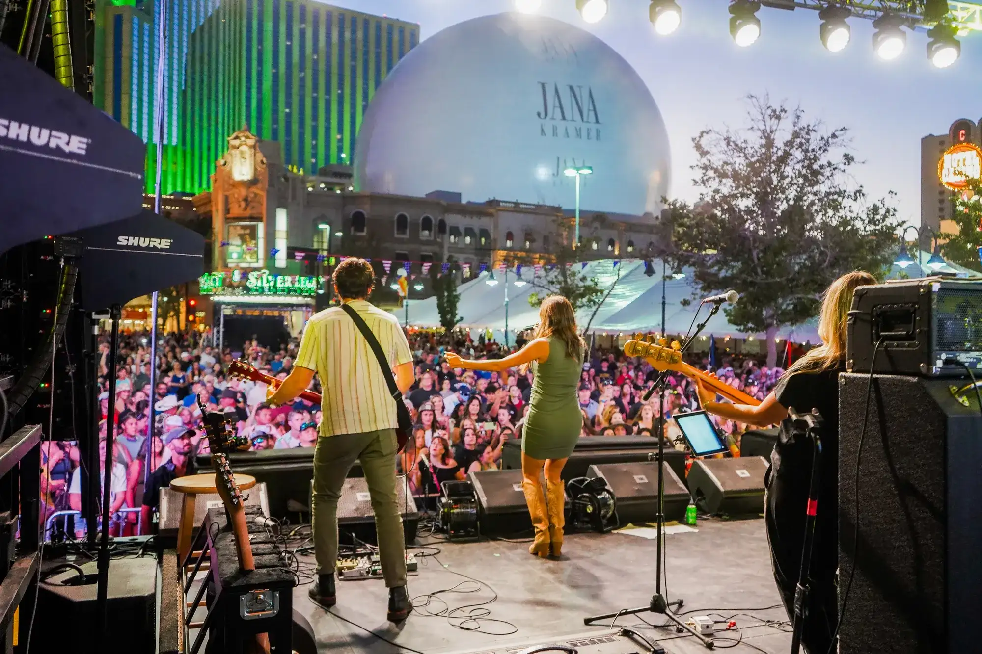 Live outdoor concert in downtown Reno with a large festival crowd, stage lights, and casino resort buildings in the background