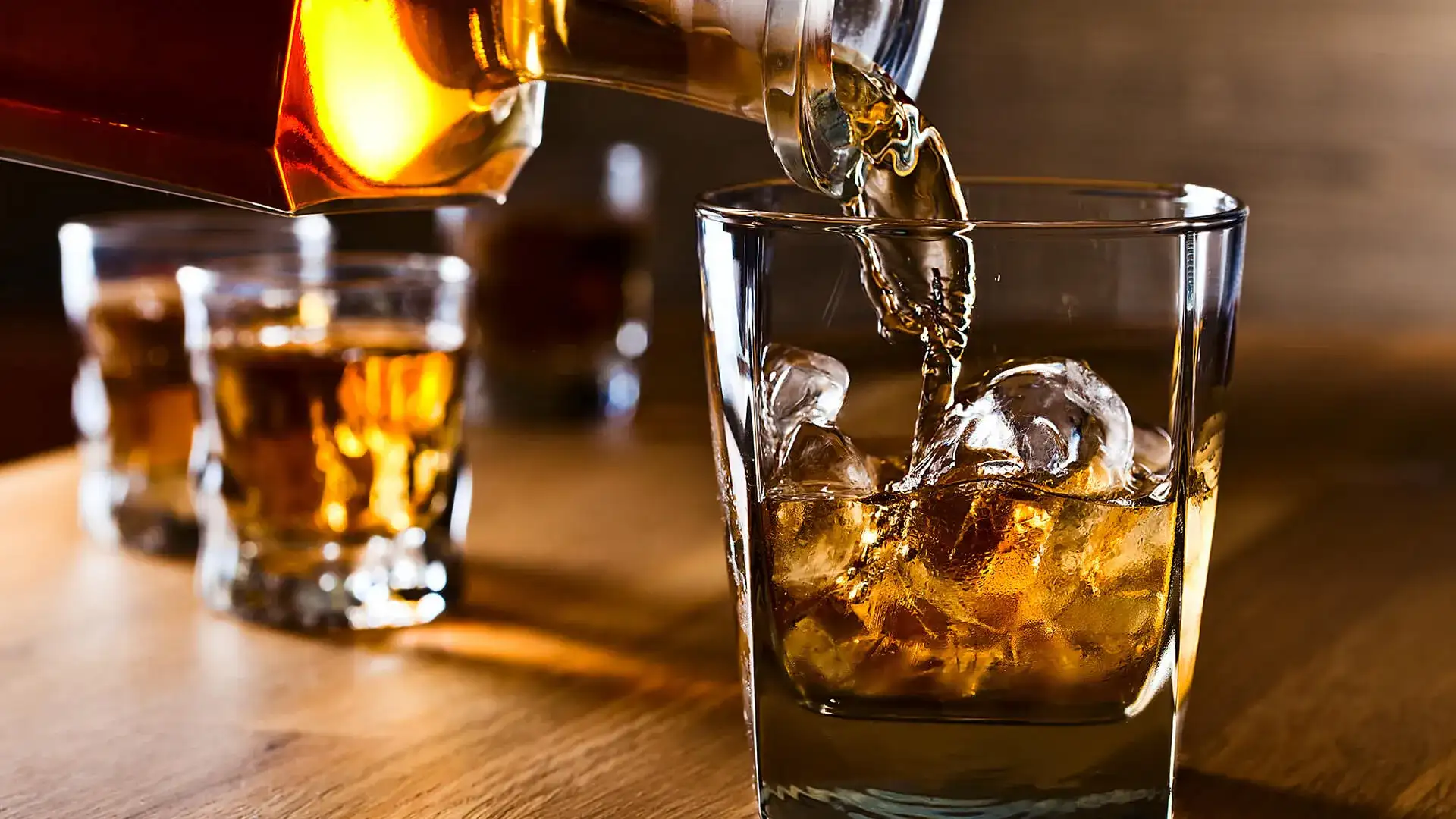 bourbon being poured into a glass with ice