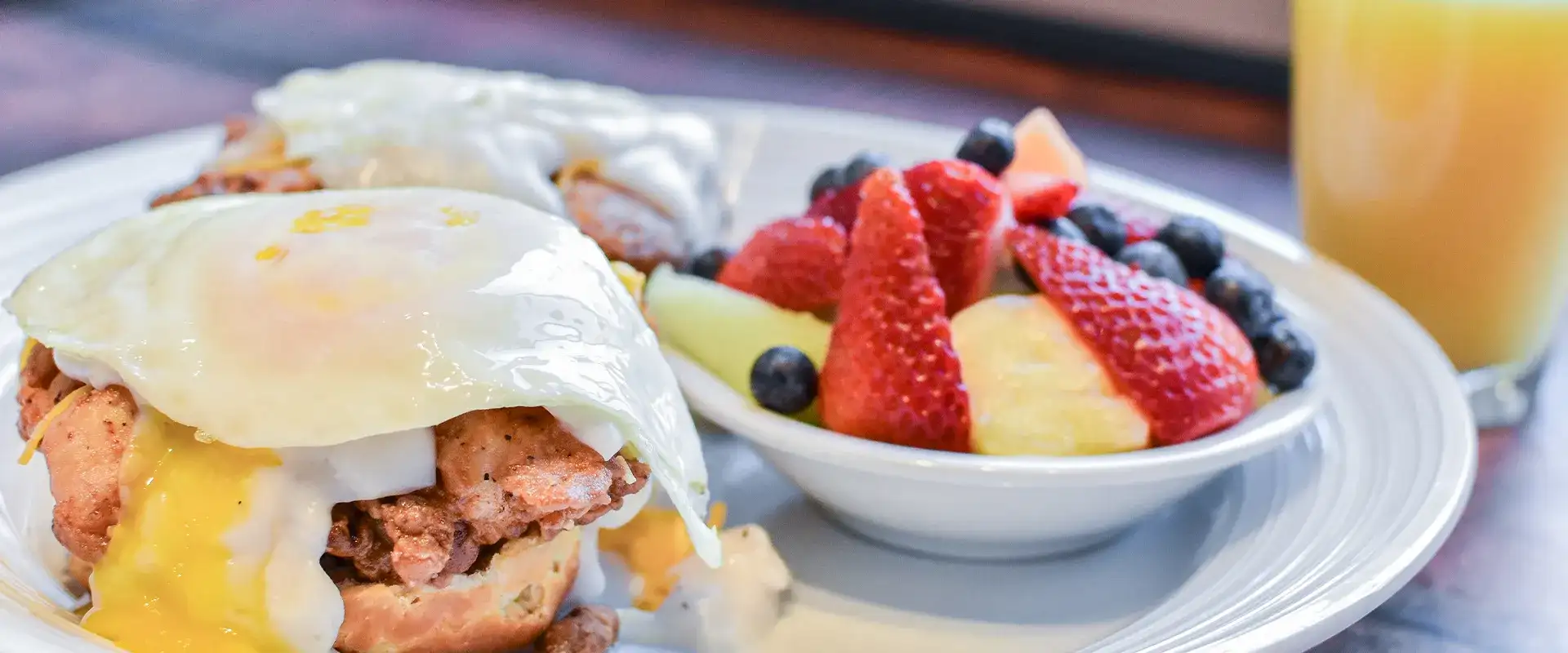 Eggs benedict, fruit bowl, and orange juice.