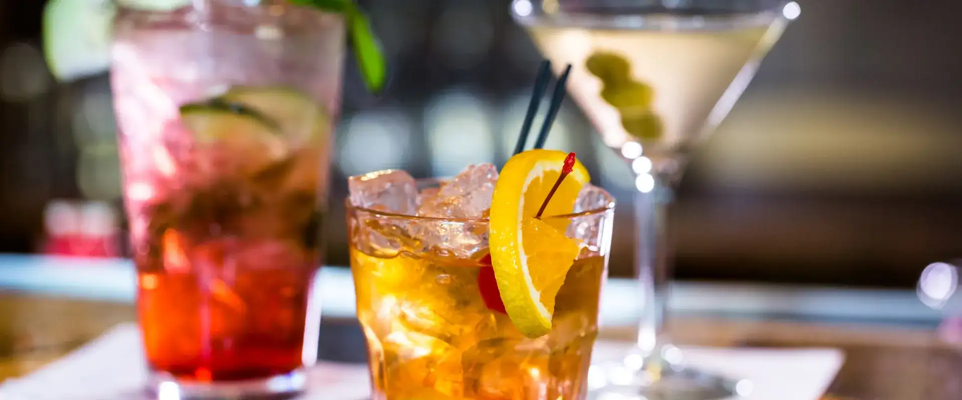 Three different alcoholic beverages sitting on the bar