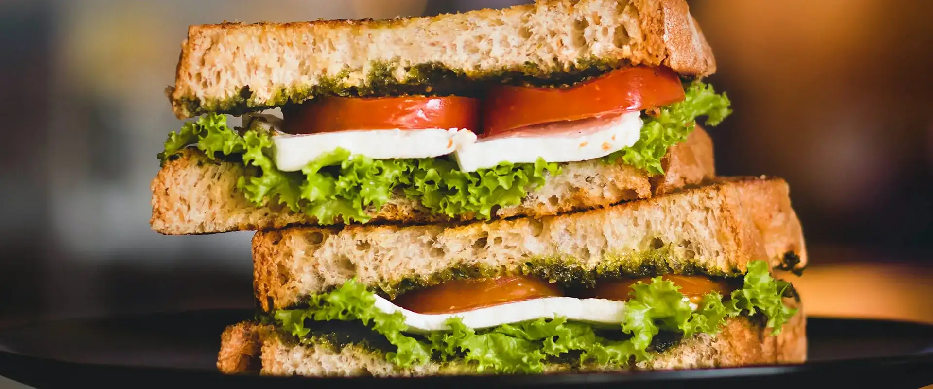 Sandwich with tomato, pesto, lettuce, and mozzarella