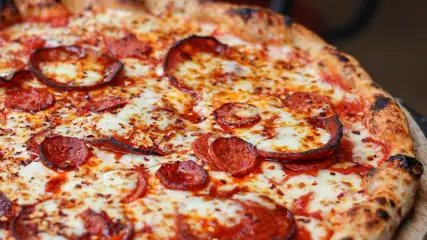 Thin crust pizza on a wooden peel.