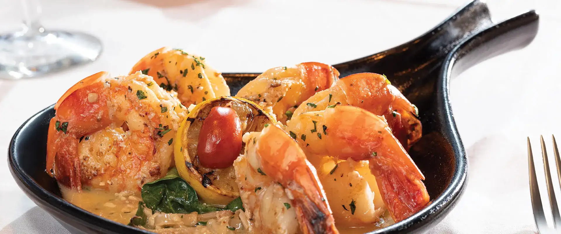 Shrimp in a white wine sauce with lemon garnish.
