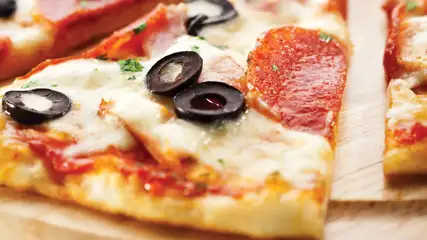 Piece of pizza with pepperoni and olives.