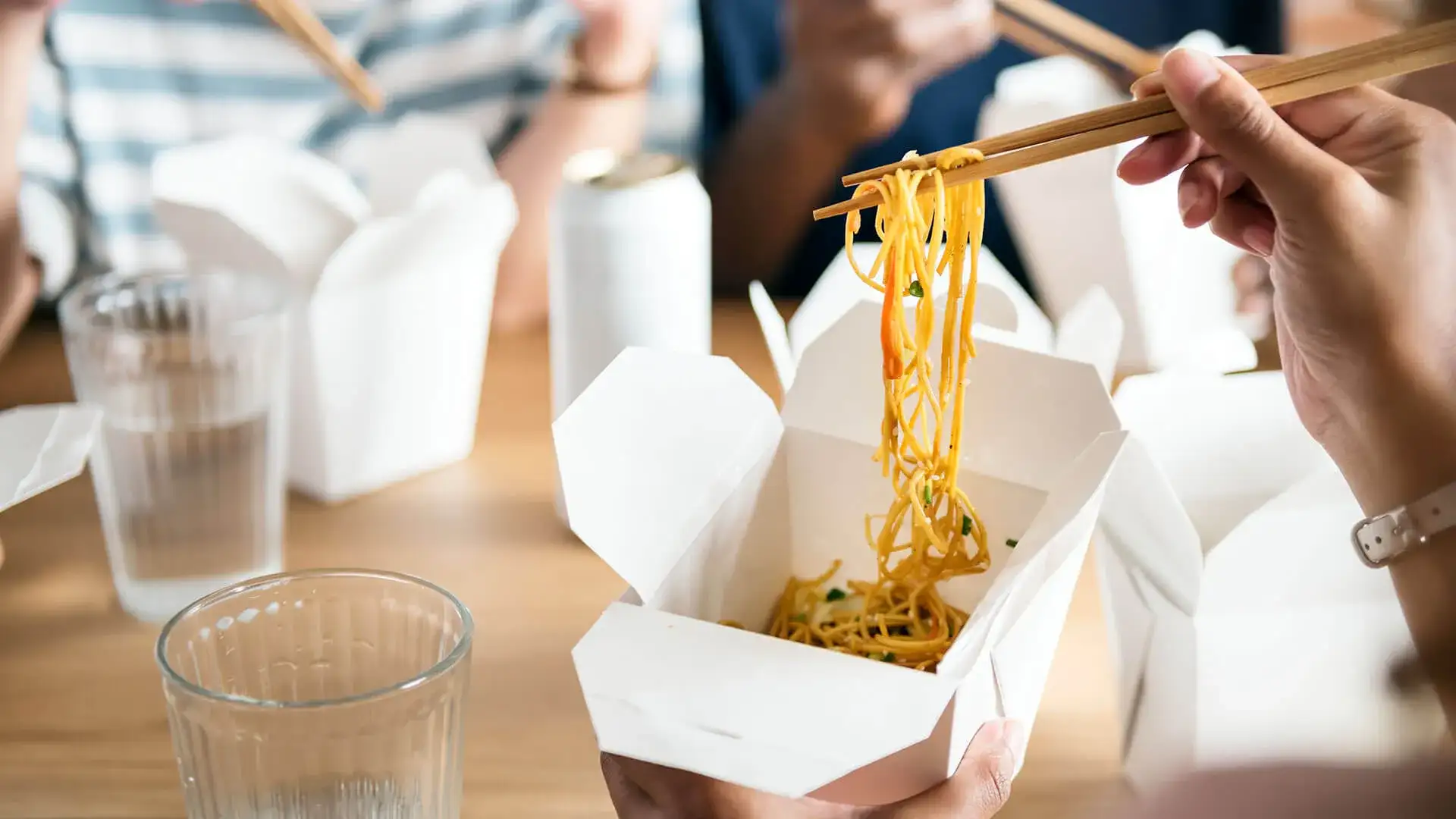 Person lifting noodles out of takeout container.