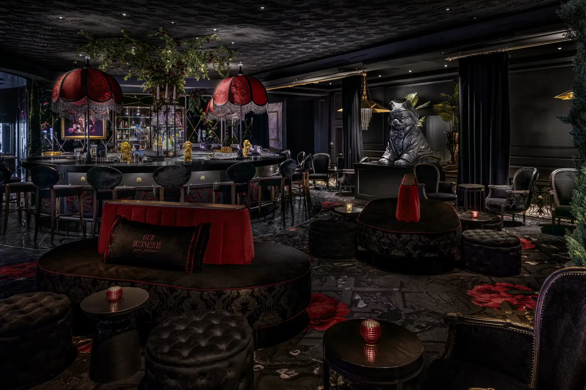 Gigolo Cocktail Lounge interior at The Vanderpump Hotel Las Vegas featuring Lisa Vanderpump's signature design with red chandelier shades, black velvet banquettes, a central circular bar, and a sculptural tribute to her late Pomeranian Giggy