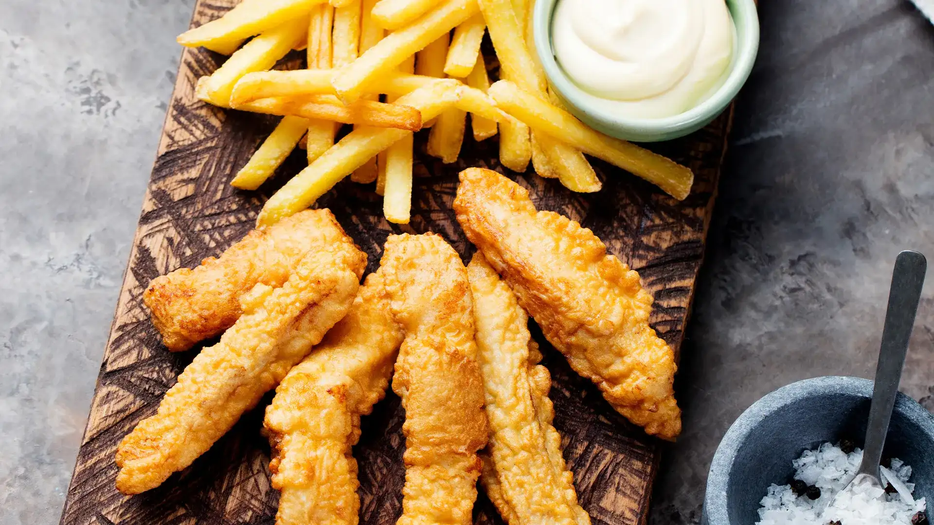 Chicken strips, fries, and aioli on a platter.
