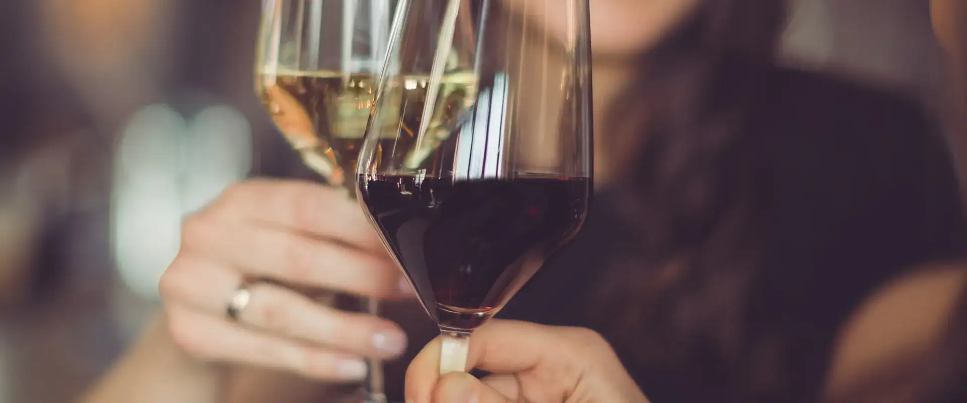 Two people toasting with red and white wine.