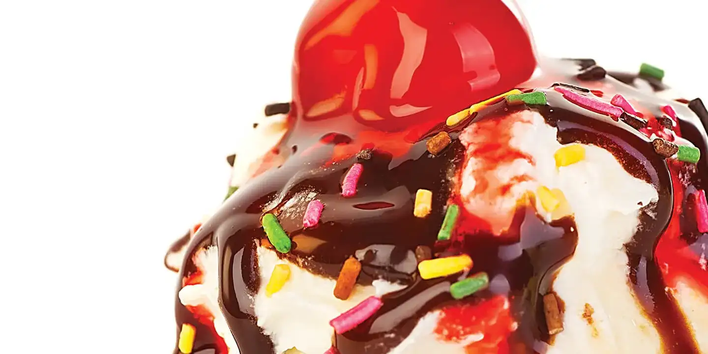 Ice cream with chocolate sauce, sprinkles and a cherry on top.
