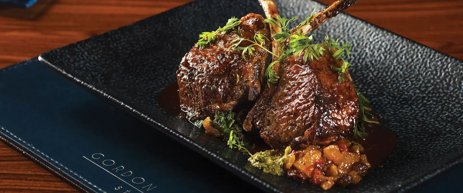 Lamb chops plated and garnished with fresh parsley sprigs.
