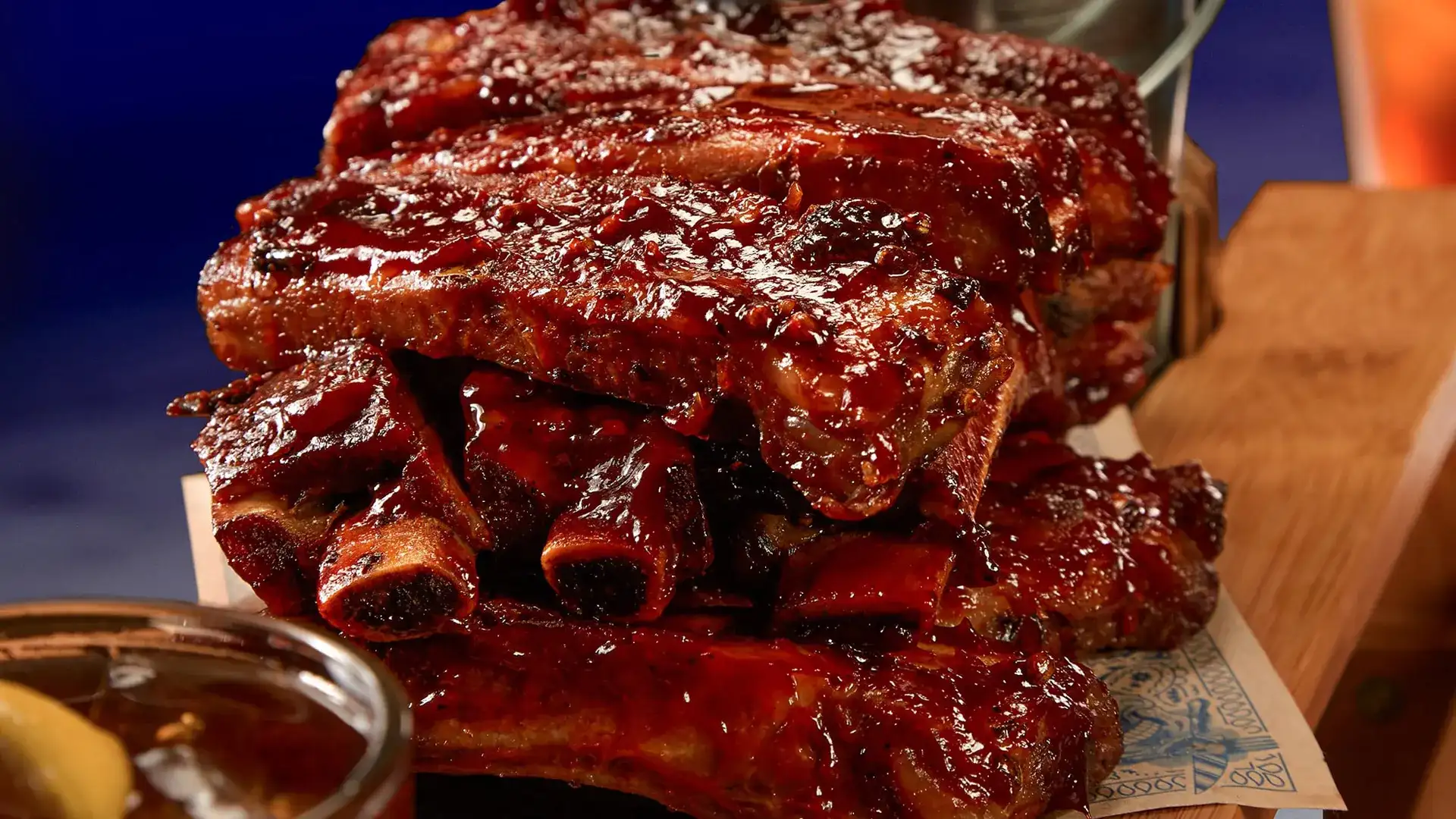 BBQ ribs stacked on a wooden platter.