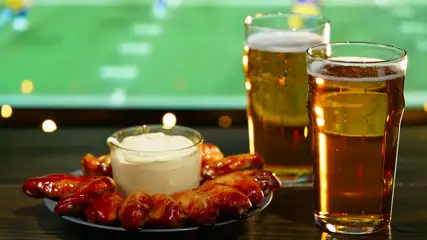 Chicken wings and 2 glasses of beer sitting on a table