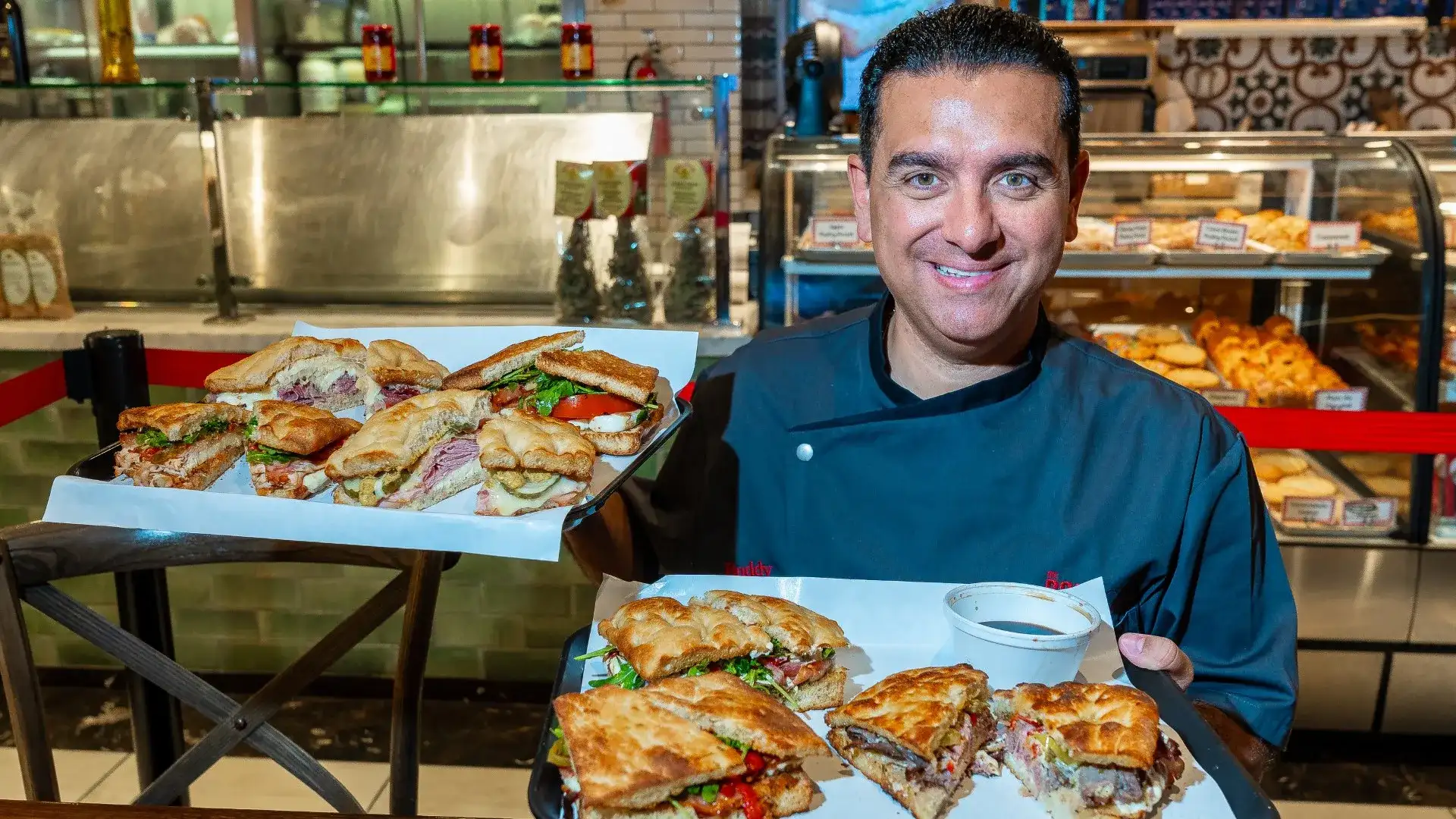 Buddy Valastro holding two trays of different sandwiches