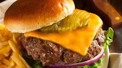 Cheeseburger with pickles, onion, lettuce, and fries on the side.