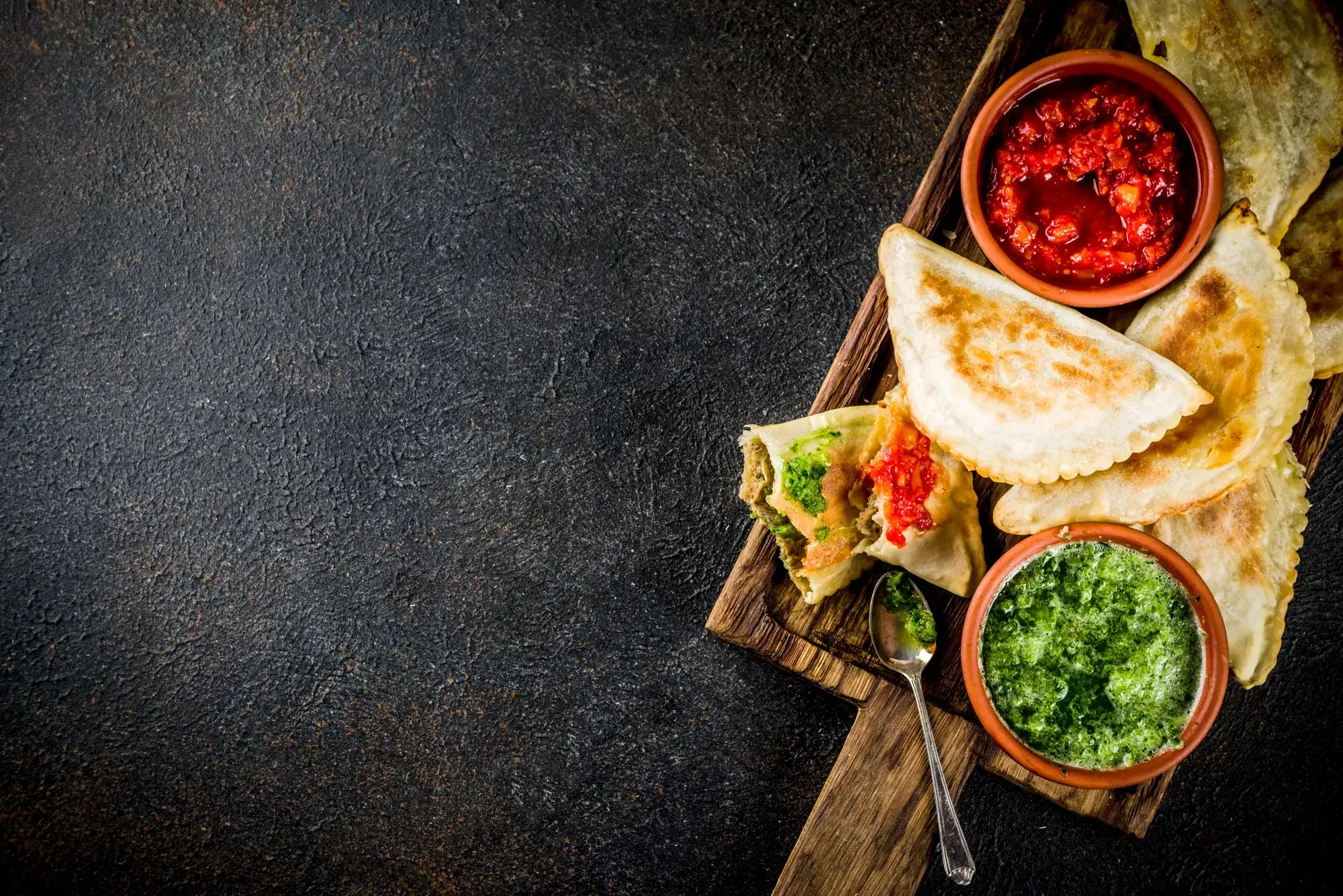 Mexican food plated on a board next to two sauces