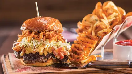 Huge burger with a side of curly cut fries from Guy Fieri's Vegas Kitchen and Bar